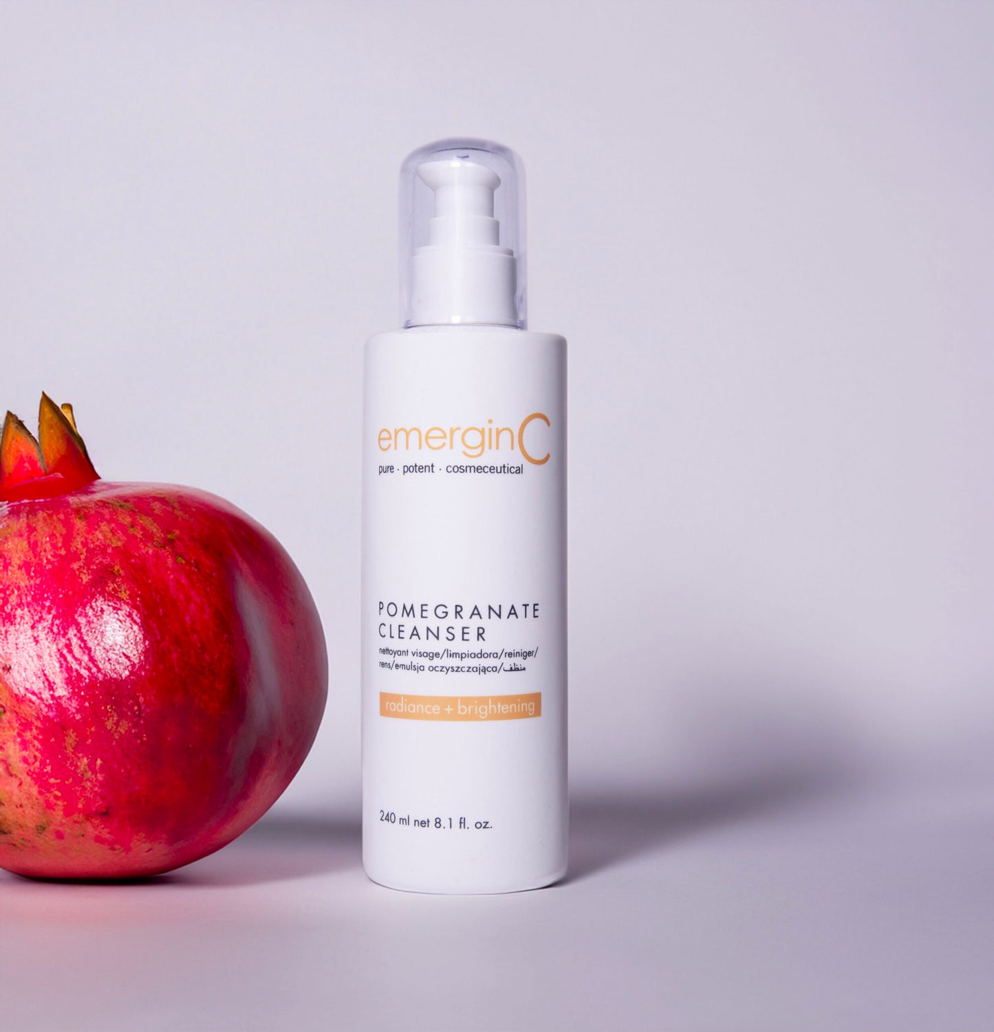 Container of emerginC Pomegranate Cleanser next to a pomegranate